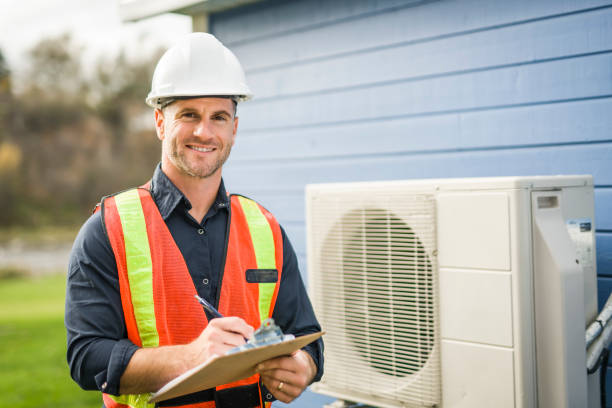 A technician working on air conditioning or heat pump outdoor unit HVAC Contractor installing efficient heating system for Dearborn, MI home comfort